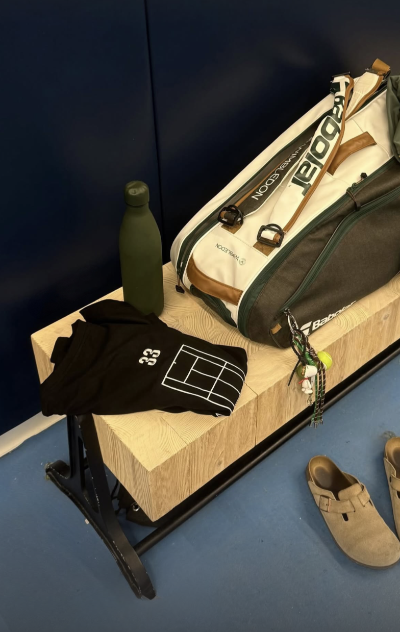 Tennis racket bag, shirt, and shoes on a wooden block with a dark background